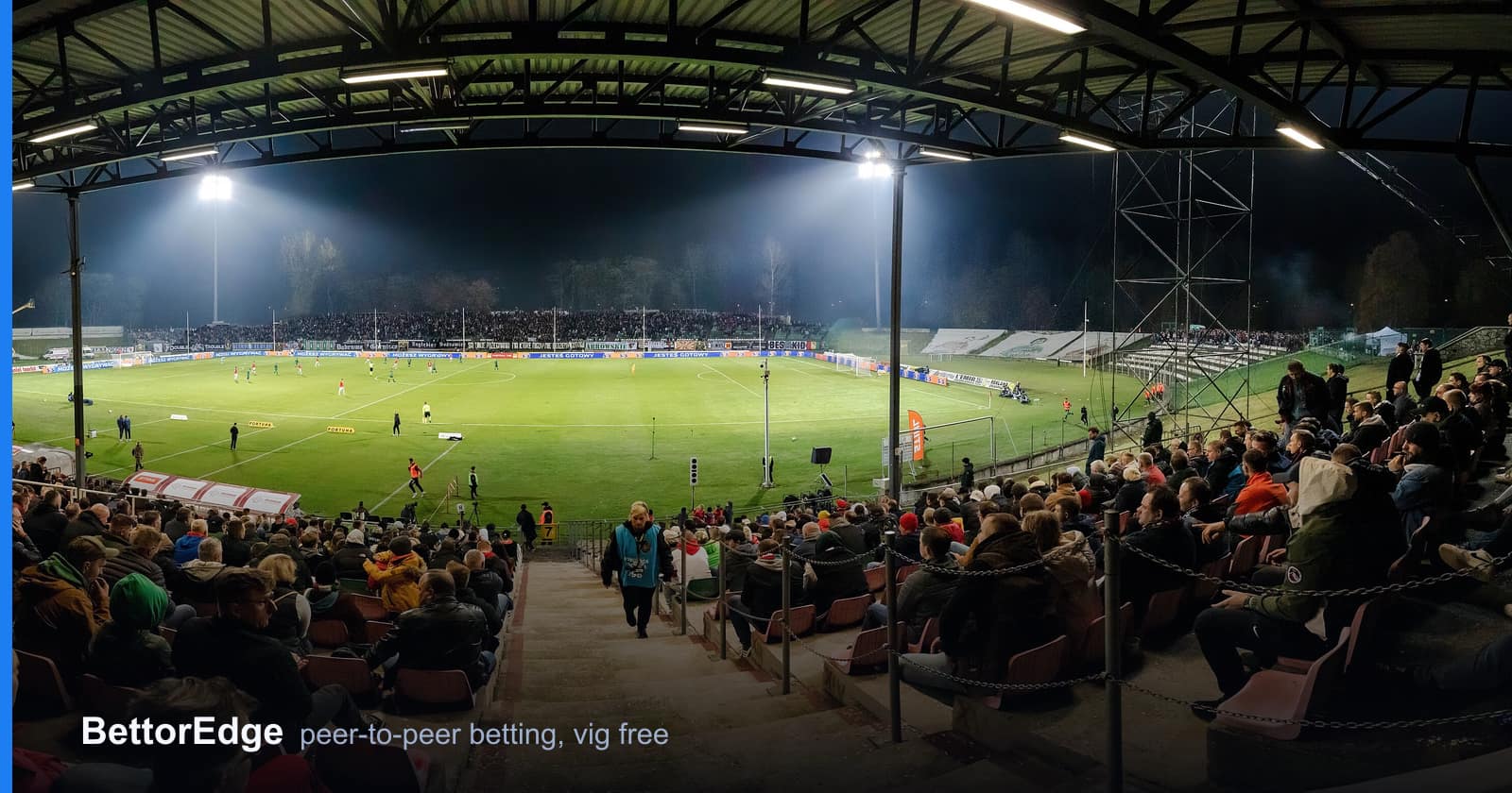 A floodlit soccer match in front of a full stand